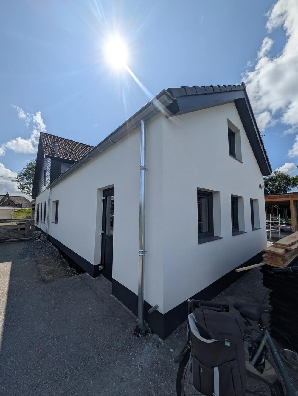 Gevel in kalkstuc met strak gestucte neggen en donkere plint